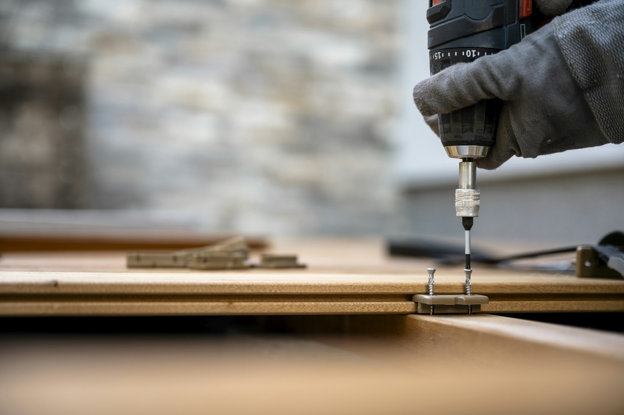 Battery screwdriver fixating screws in plastic distance marker for wooden outside patio